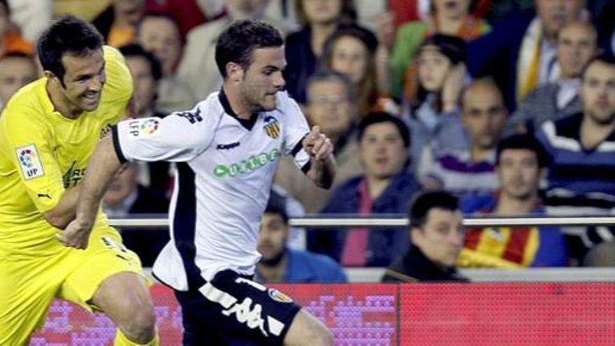 El delantero del Valencia CF Juan Mata (d) disputa el balón con el defensa del Villarreal CF Carlos Marchena (i).