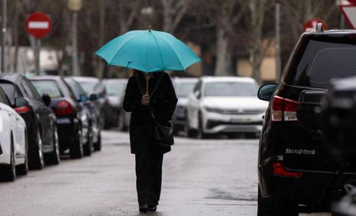 Una dona abrigada amb un paraigua en un dia de pluja