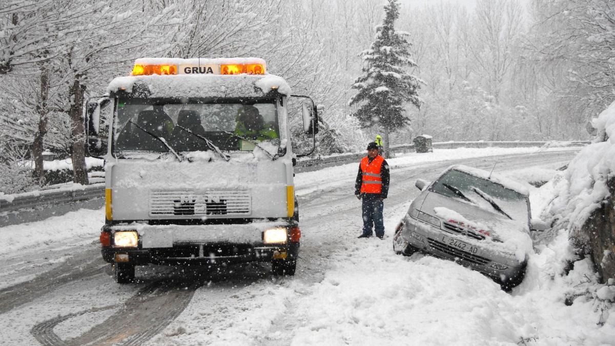 Una grúa atiende a un coche atrapado en la nieve en una carretera de Rialp.