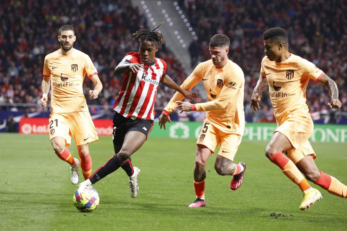 MADRID, 19/02/2023.- El delantero del Athletic Club, Nico Williams (2i), con el balón ante los jugadores del Atlético de Madrid, el argentino Rodrigo de Paul (2d) y el mozambiqueño Reinildo Mandava, durante el encuentro correspondiente a la jornada 22 que disputan hoy domingo en el estadio Metropolitano, en Madrid. EFE / Juan Carlos Hidalgo.