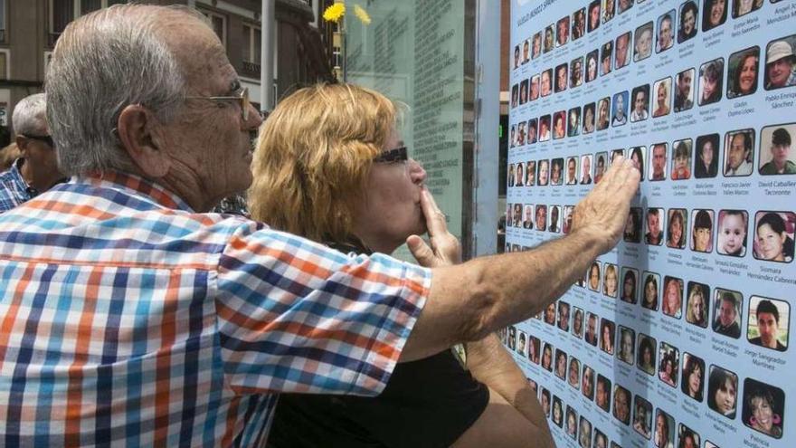 Familiares frente al mural con nombres y fotografías de las víctimas en la plaza de la Memoria de las Palmas.