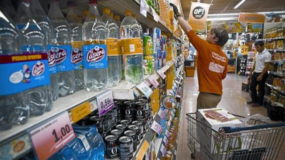 Un trabajador repone bebidas en un supermercado.