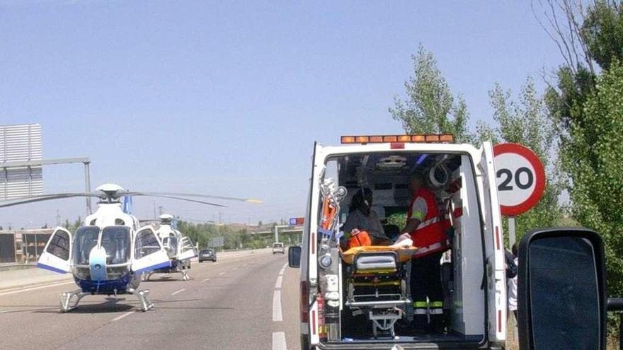 Efectivos sanitarios durante una asistencia en carretera, con helicóptero y ambulancia.