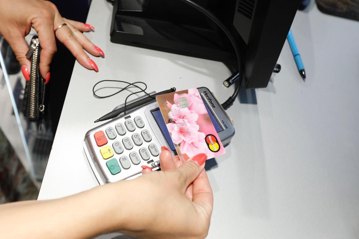 Señora pagando con una tarjeta de crédito con un diseño de rosas.