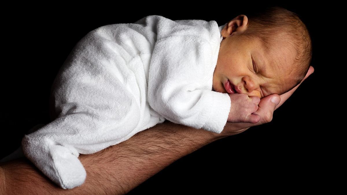 Un bebé duerme sobre el brazo de un hombre