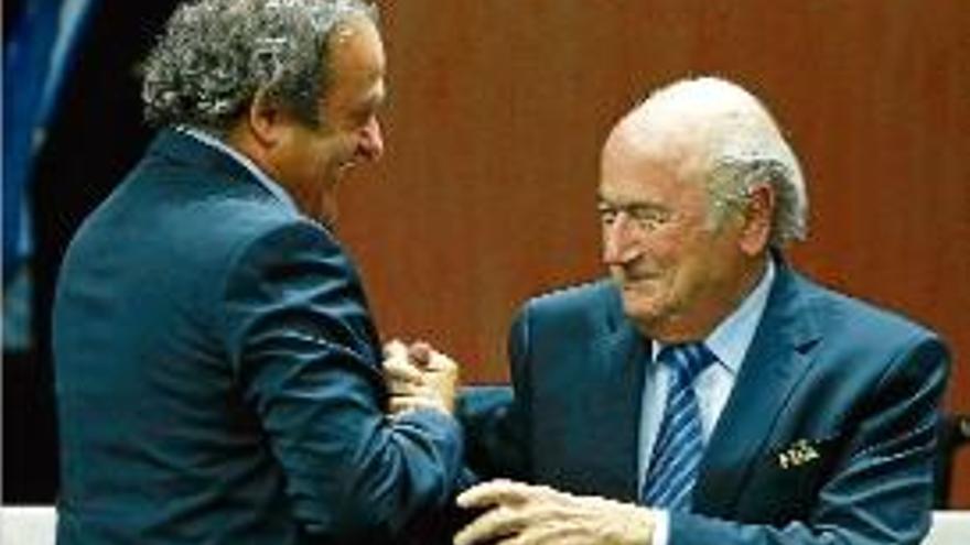 Michel Platini i Joseph Blatter somriuen mentre se saluden.