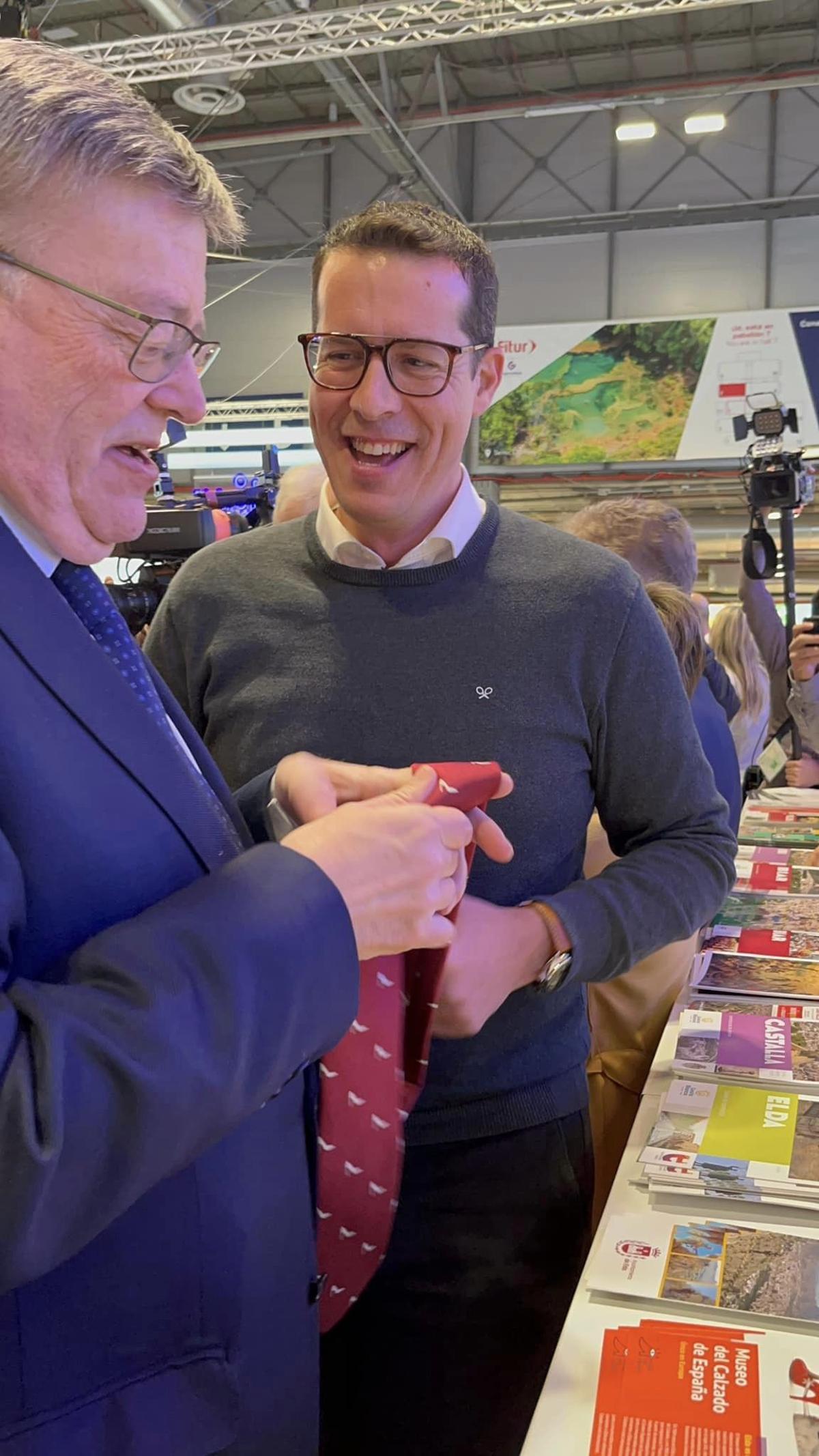 Ximo Puig con la corbata de los zapatos de Elda que el alcalde Rubén Alfaro le entregó en Fitur.