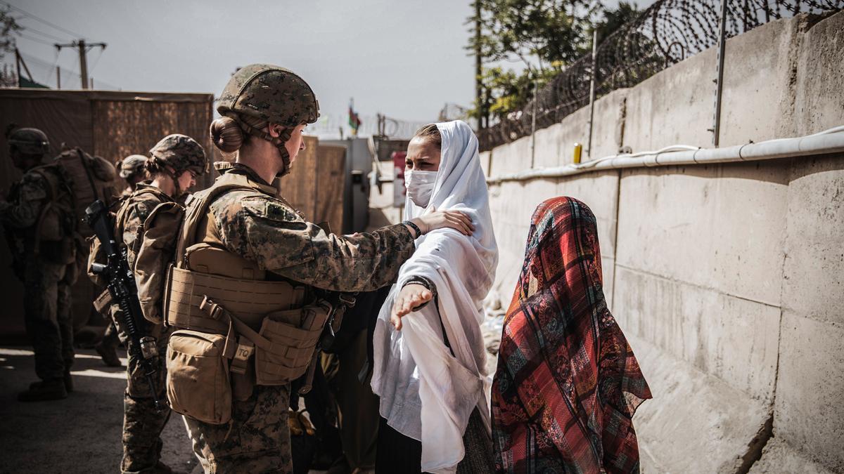 Una marine examinando a una mujer a su entrada en el aeropuerto de Kabul.