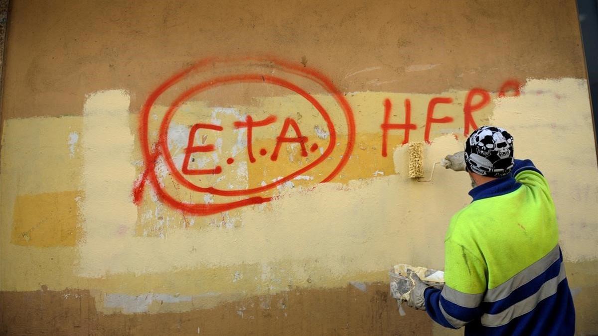 Un operario borra una pintada en la que aún se puede leer ETA