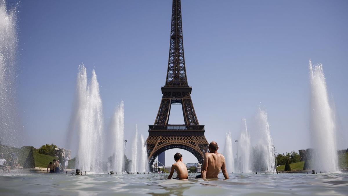 Un hombre y un niño se refrescan en una fuente frente a la Torre Eiffel de París, el pasado verano, en plena ola de calor.