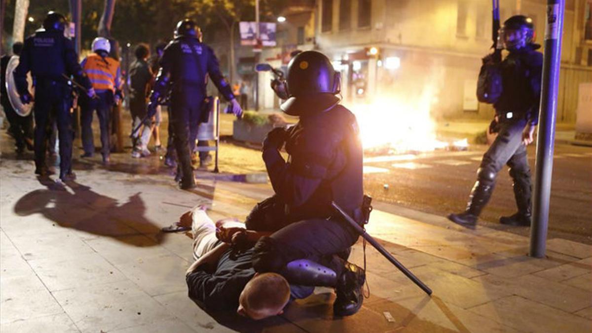 Un agente de policía retiene en el suelo a un detenido tras los disturbios de esta noche.