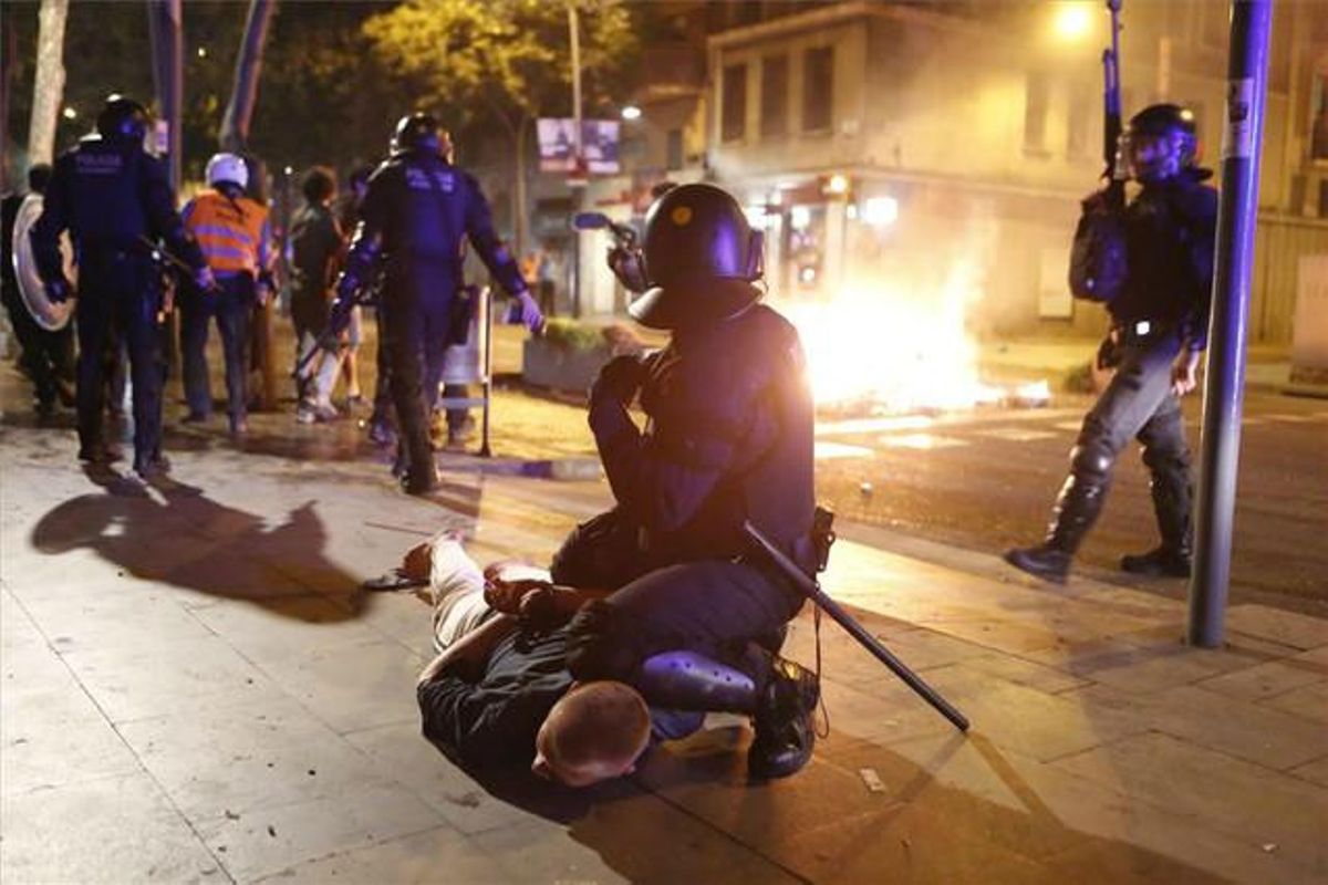 Un agent de policia reté a terra un detingut després dels disturbis daquesta nit.