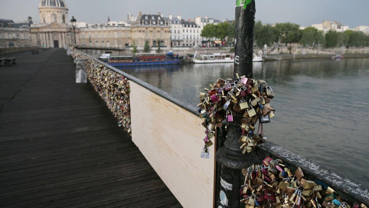 El Puente de las Artes de París, lleno de candados y con el tablón que cubre la parte que ha cedido, este domingo.