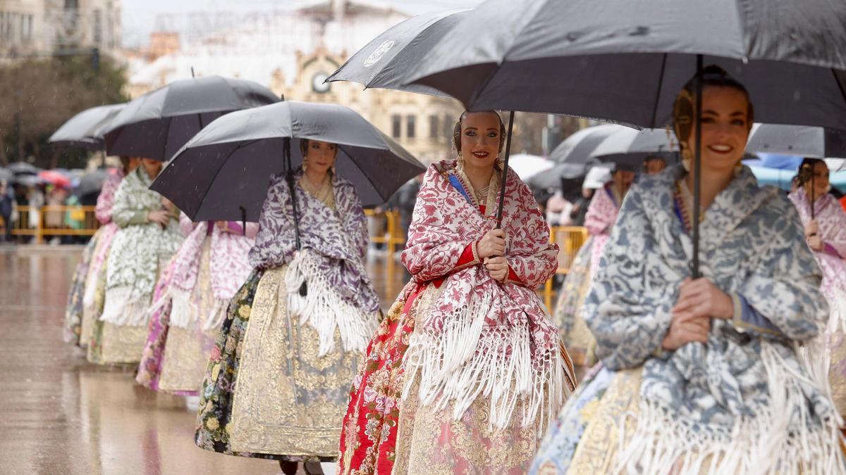 La Corte de las Falleras Mayores llega al ayuntamiento protegidas con paraguas.