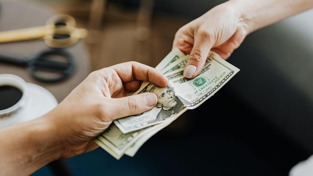 Persona pagando en efectivo con dólares.