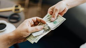 Persona pagando en efectivo con dólares.