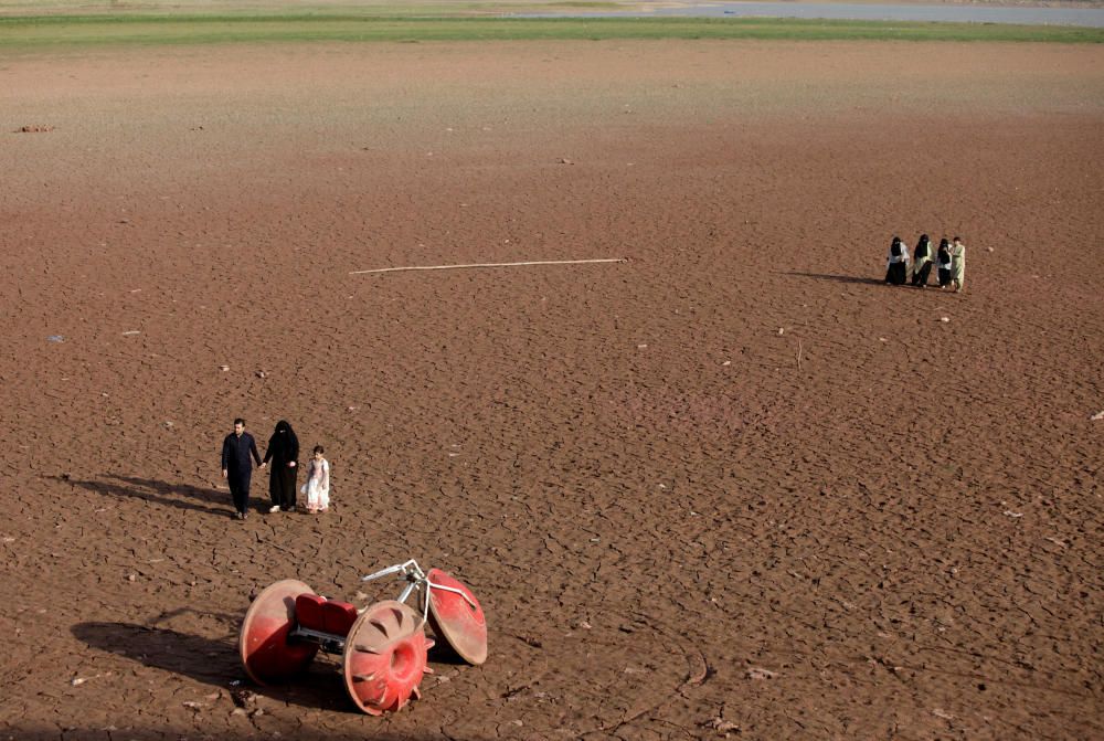 People walk near a three-wheeler parked at a dry ...