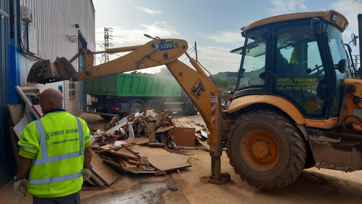 Una excavadora recoge rediduos para cargarlos en un camión.