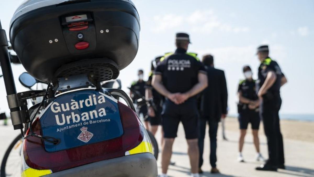 Agentes de la Guardia Urbana de Barcelona, junto a una motocicleta del cuerpo de seguridad