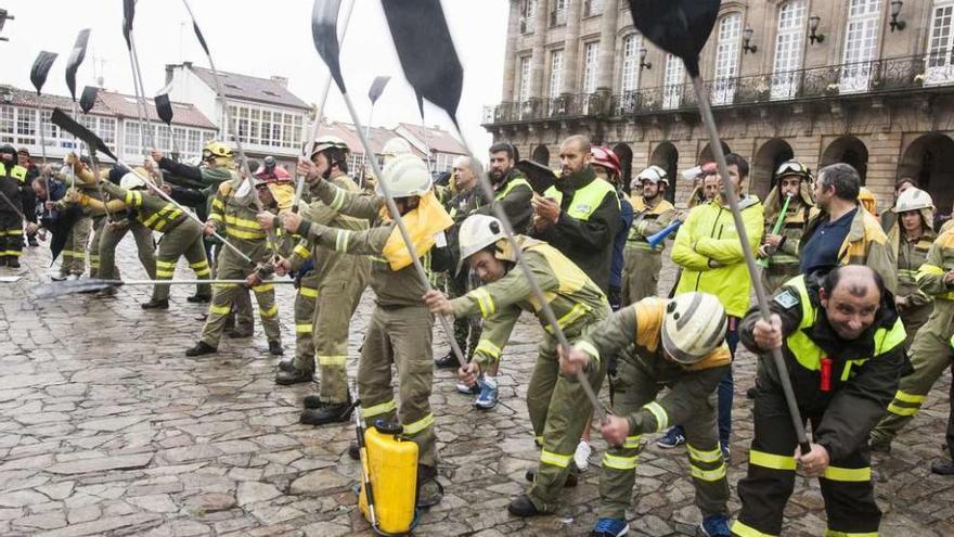 Operarios antiincendios, ayer en la plaza del Obradoiro, golpeando el suelo con los batefuegos en protesta por sus malas condiciones laborales.