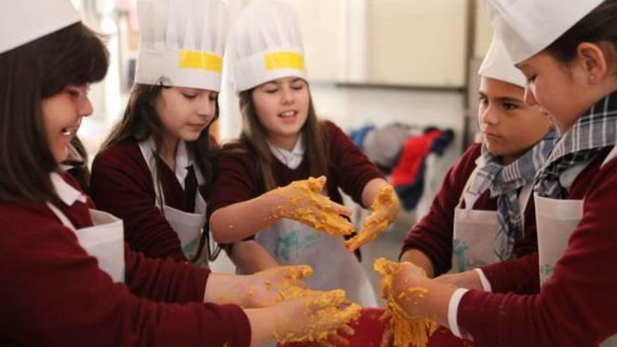 Un grupo de menores elaboran la masa para cocinar buñuelos de calabaza en Sueca.