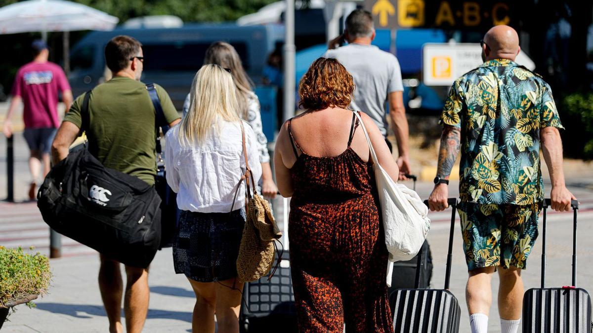 Turistas, ayer, arrastran sus maletas en la zona exterior de la terminal del aeropuerto. | TONI ESCOBAR