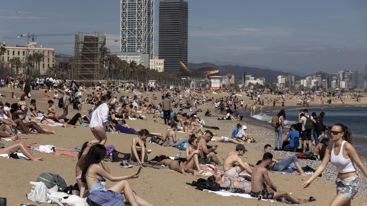 Gente tomando el sol en la playa de la Barceloneta.