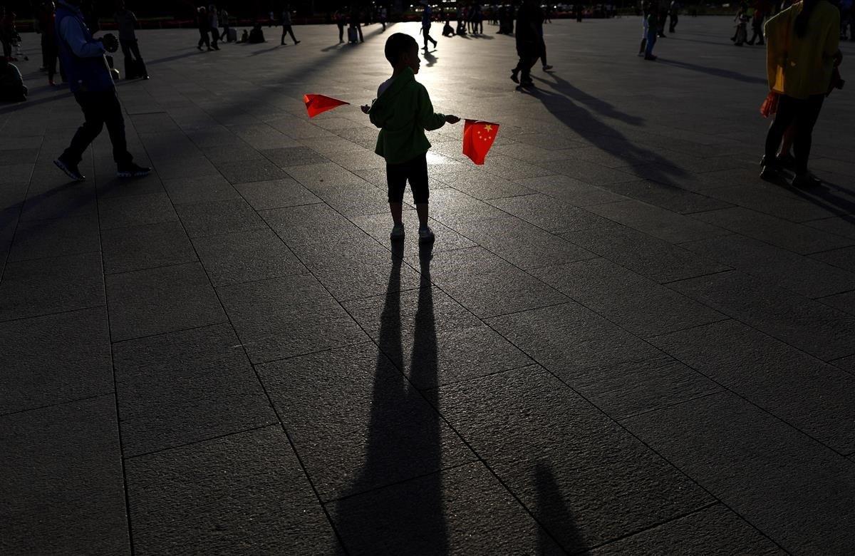 Un niño sostiene dos banderas en la plaza de Tiananmen en Pekín. El Gobierno de China afronta este martes uno de los aniversarios más dolorosos de su historia -el trigésimo desde la matanza de Tiananmen- sin asumir responsabilidades al negar las evidencias y criminalizando a las víctimas de la represión que acabó con la protesta estudiantil.