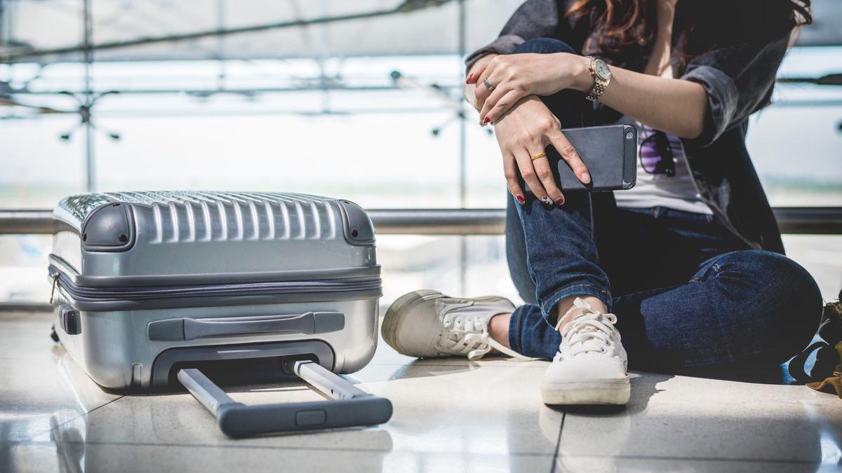 Una mujer junto a su maleta en el aeropuerto.