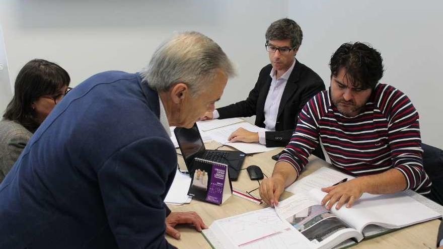 Luis Taboada examina los planos bajo la mirada de María del Carmen Silva y Gregorio Agís.