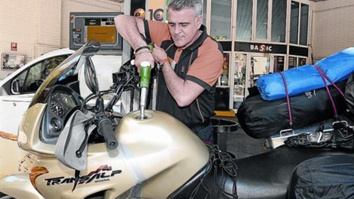 Un trabajador de una gasolinera llenando el depósito de una moto ayer, en Barcelona.