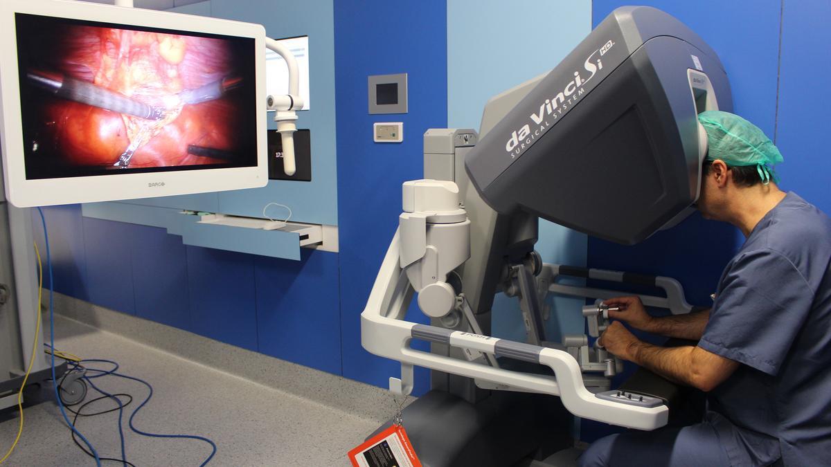 El cirujano moviendo a distancia desde una consola los brazos robóticos del Da Vinci.