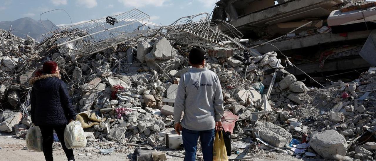 Dos habitantes de Alejandreta observan un edificio derrumbado por el terremoto.