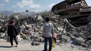 Dos habitantes de Alejandreta observan un edificio derrumbado por el terremoto.