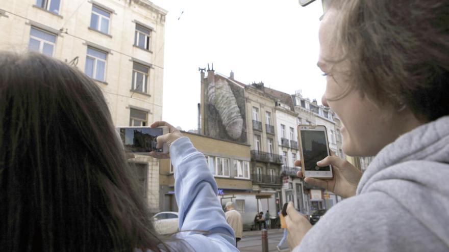 Dos jóvenes fotografían el peculiar arte urbano. // Efe