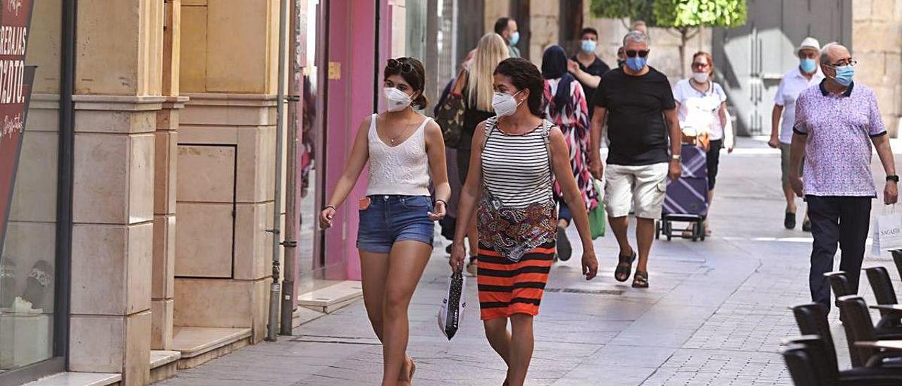 Vecinos de Elche, donde se han producido cinco brotes en un día, caminan con la mascarilla por la calle.