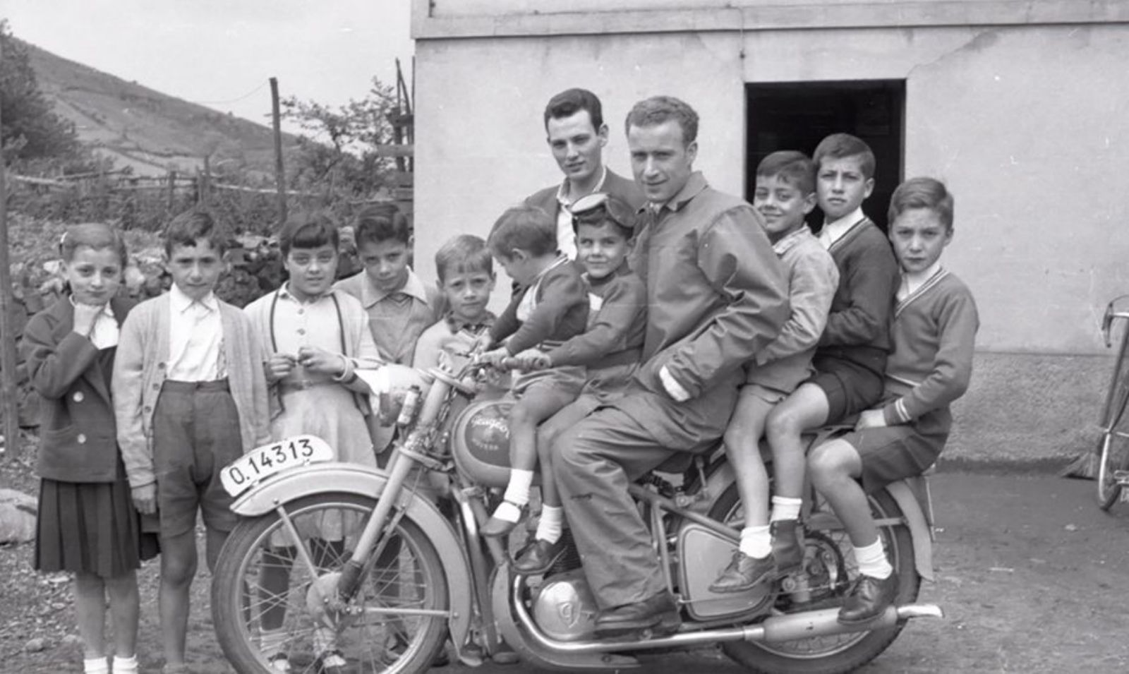 Un grupo de niños posan junto a un motorista. 