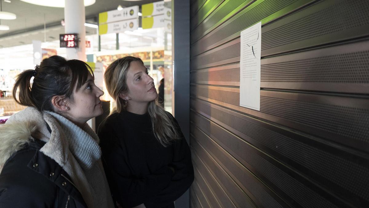 Stephanie Guzmán i Júlia Fernández mirant el cartell que anuncia el tancament del centre Ideal a Manresa