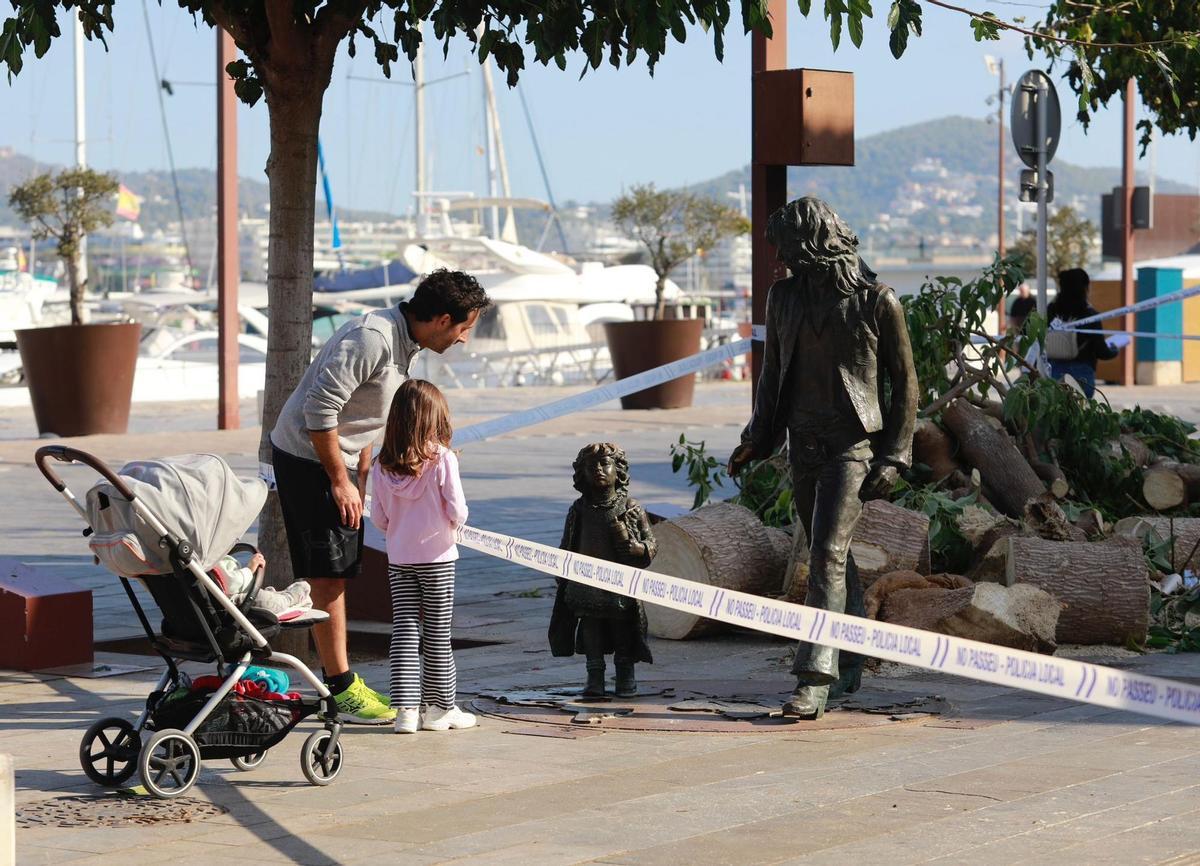 Un hombre y una niña observan la estatua, precintada por la Policía Local de Ibiza
