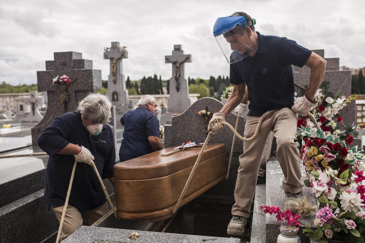 Trabajadores del cementerio de La Almudena entierran el ataúd de Manuela Revuelta. Manuela, 94 años, falleció el 4 de abril en una residencia de ancianos, a consecuencia de la covid-19. Madrid, 7 de abril, 2020