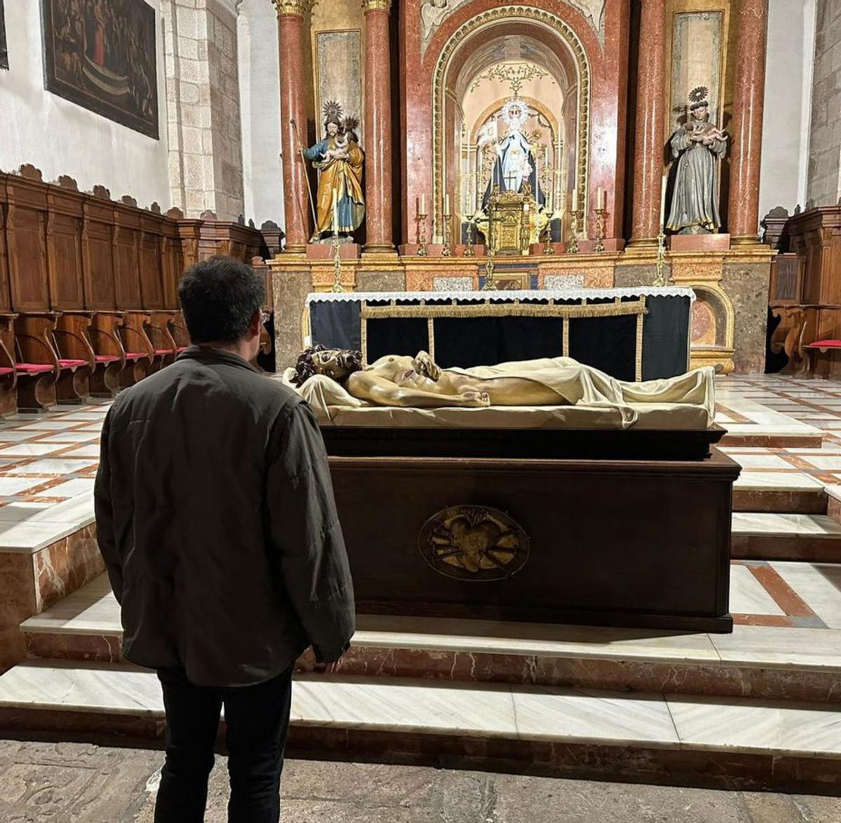 Un hombre contempla el Yacente en el altar mayor de la iglesia de San Vicente. | Cofradía de Nuestra Madre