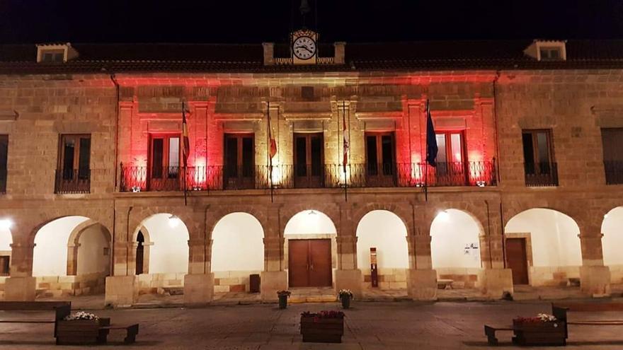 La fachada del Ayuntamiento de la Plaza Mayor de Benavente iluminada de rojo y amarillo por el Día de la Hispanidad. / E. P.