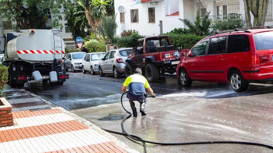 Un operario de Limpieza baldea una de las calles de Marbella.