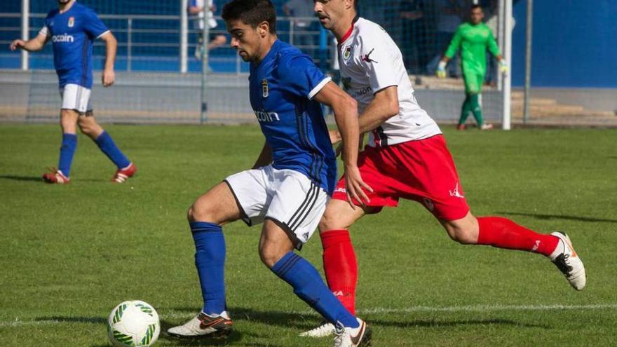 David Álvarez, del Oviedo B, protege el balón ante la presión del jugador del Langreo Nacho Calvillo.