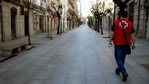 Un miembro de la Cruz Roja camina por una calle de Ourense (Galicia), vacía a causa del confinamiento por el coronavirus.