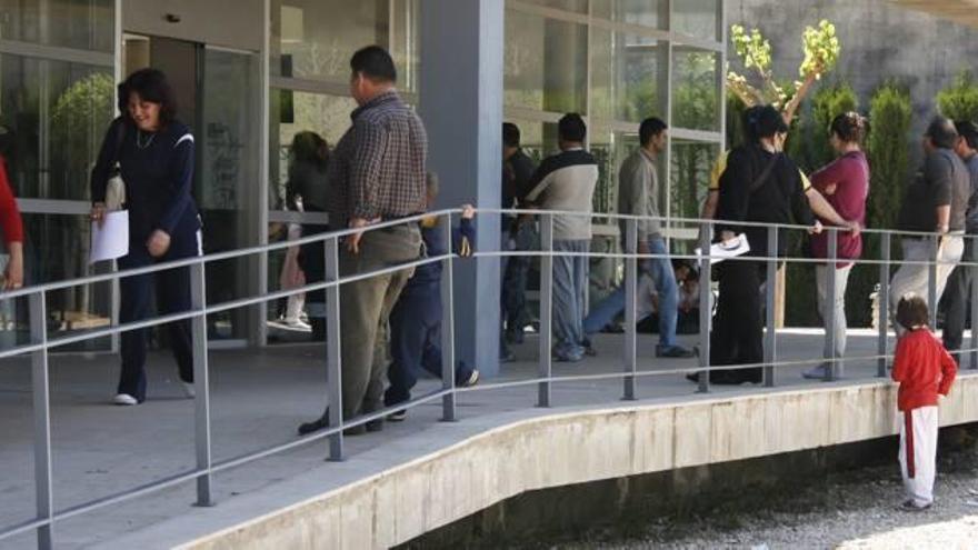 Un grupo de personas, entre ellas muchos jóvenes, en la cola del paro en Alzira.