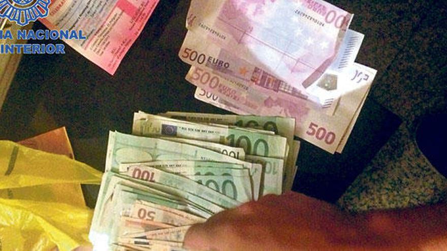 Agentes de la Policía Nacional recogen los billetes intervenidos a la banda de proxenetas nigerianos.