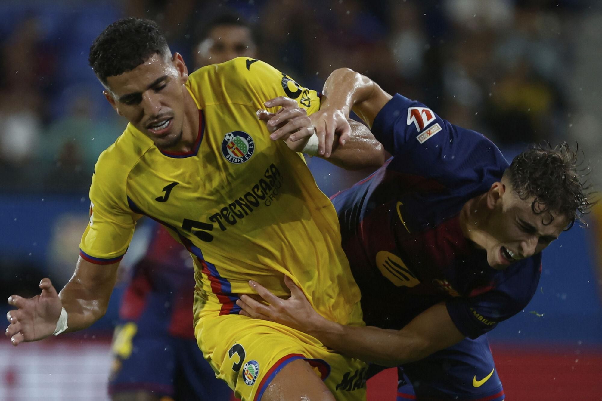 Getafe's Abdel Abqar fights for the ball against Barcelona's Fermin Lopez during a Spanish La Liga soccer match between FC Barcelona and Getafe at the Johan Cruyff stadium in Barcelona, Spain, Sunday, Sept. 21, 2025. (AP Photo/Joan Monfort)
