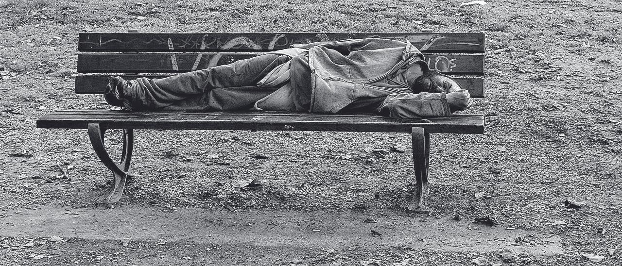 Un hombre tumbado en un banco