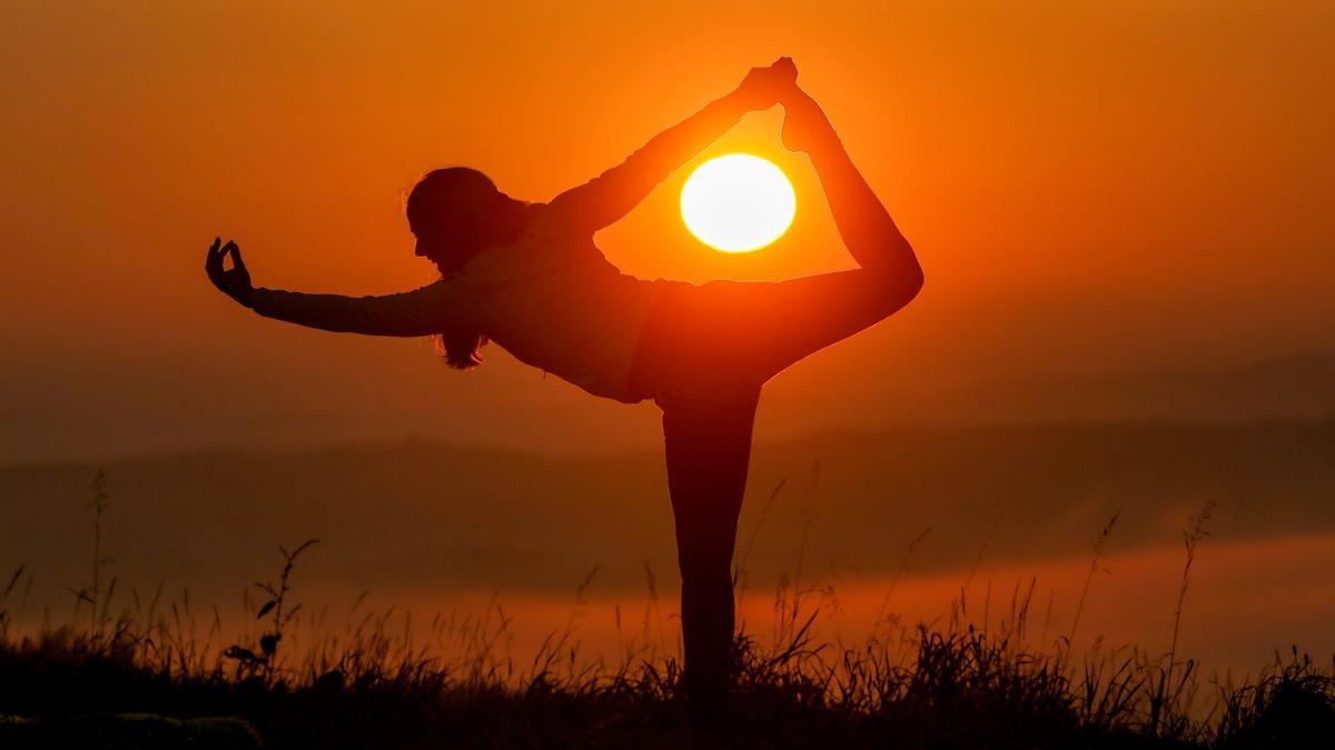 Eine Frau macht kurz nach Sonnenaufgang Yogaübungen (Symbolfoto).